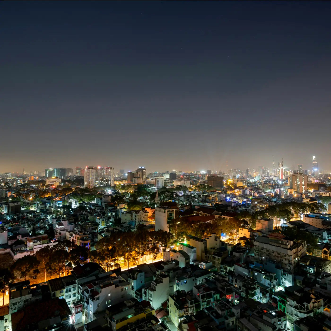 a city skyline at night. there are lots of buildings with lights on, creating light pollution in the sky. The horizon is yellow
