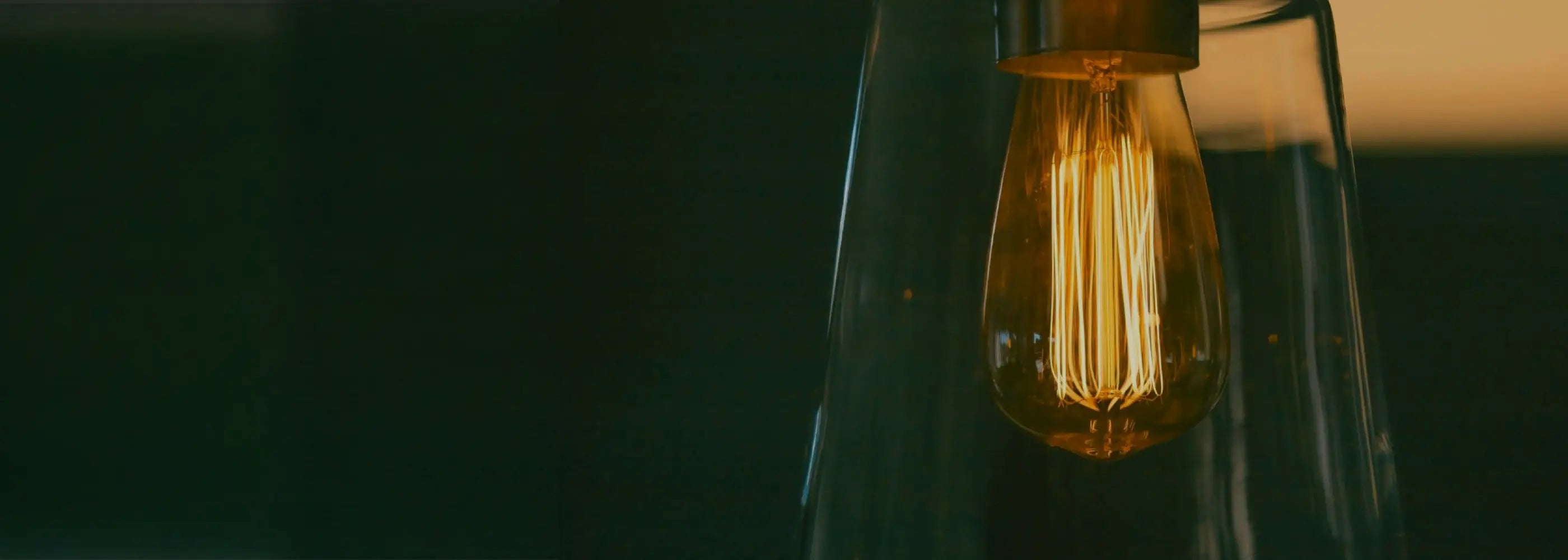 a string of outdoor light bulbs. the picture is taken at dusk, with a subtle blue and pink sky. the five lights in the picture are turned off.