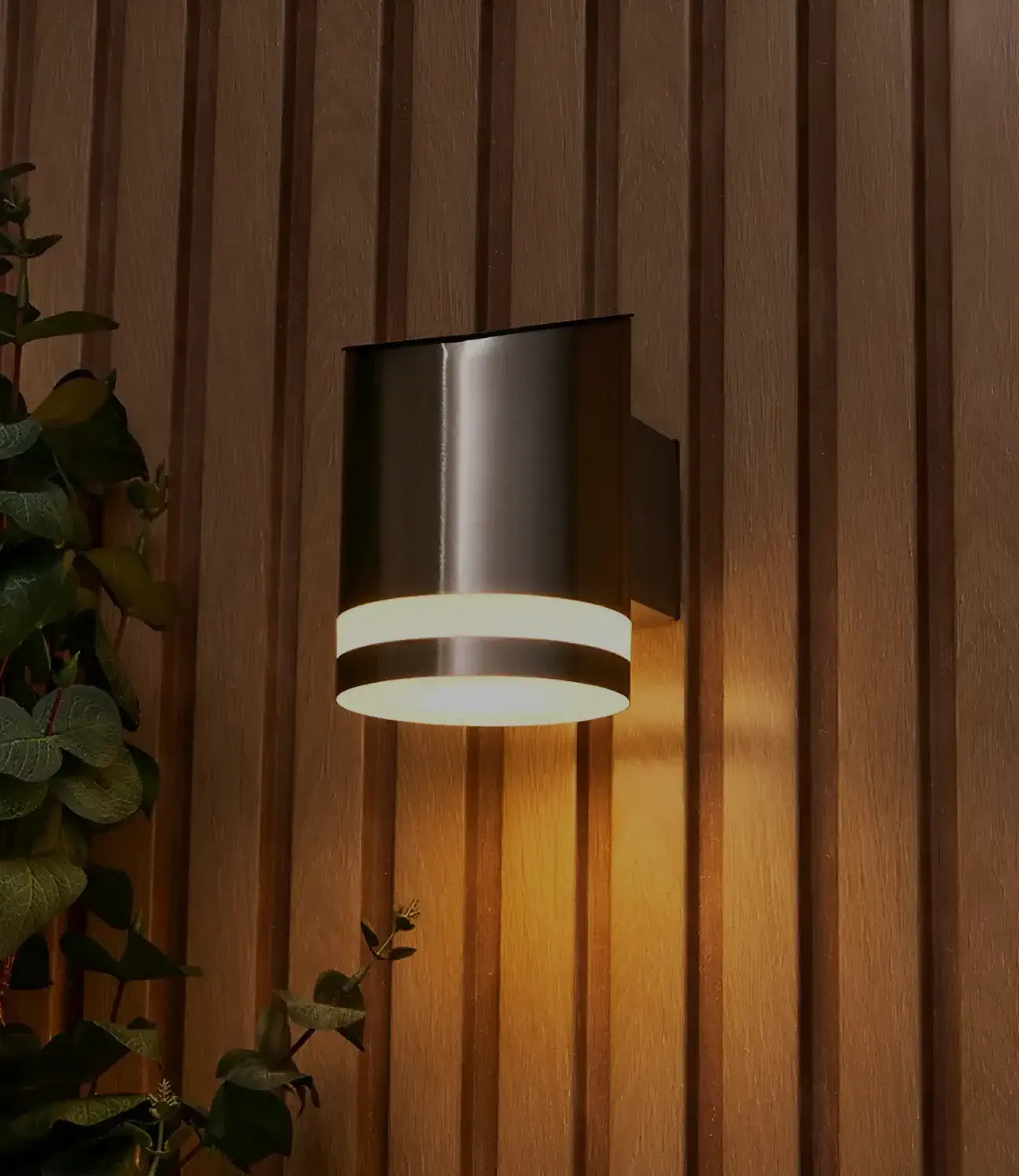 a silver solar light on a wooden panel wall next to green bushes