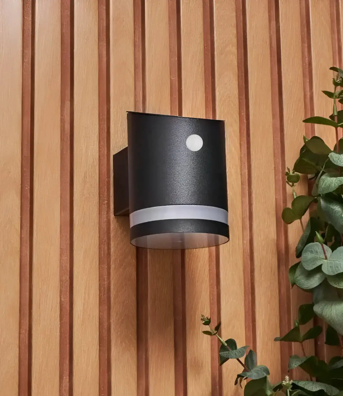 a black solar light with a motion detector on the front. The light is mounted onto a wooden wall and is turned off